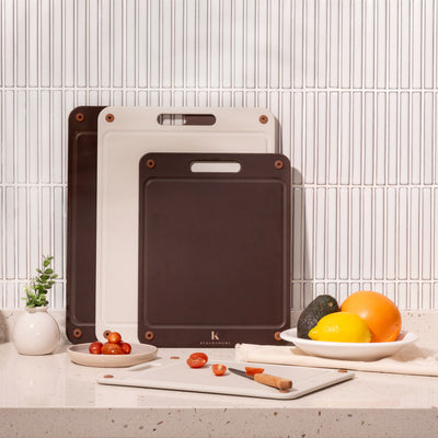 Set of four compact kai wood fibre chopping boards on a kitchen counter with fruits and vegetables.